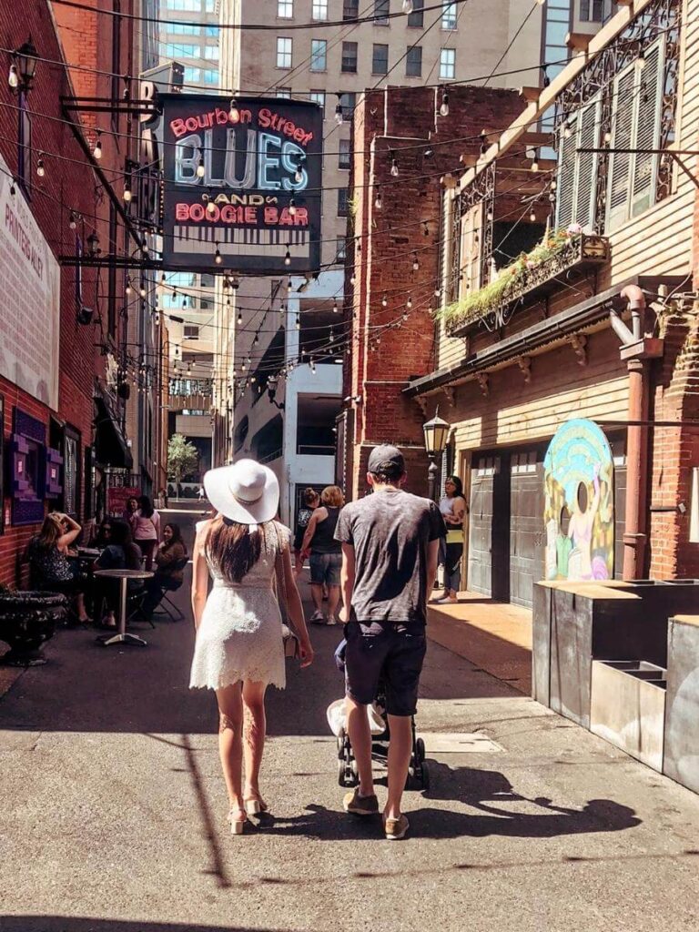Family walking down Music Row in Nashville, featuring neon signs and live music venues.
