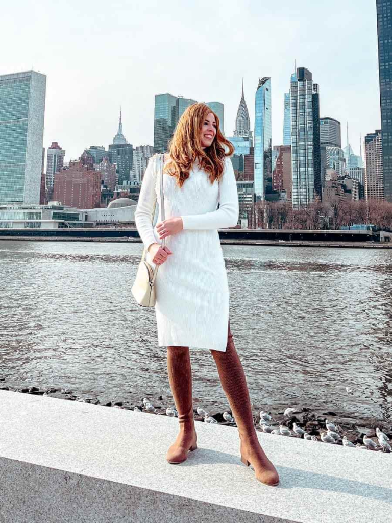 a fitted sweater dress in cream colour, styled with long boots and a luxury bag..