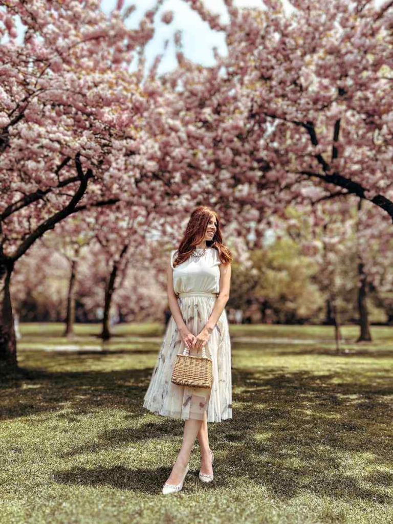 Mum in the City standing beneath blooming cherry blossoms at Brooklyn Botanic Garden.
