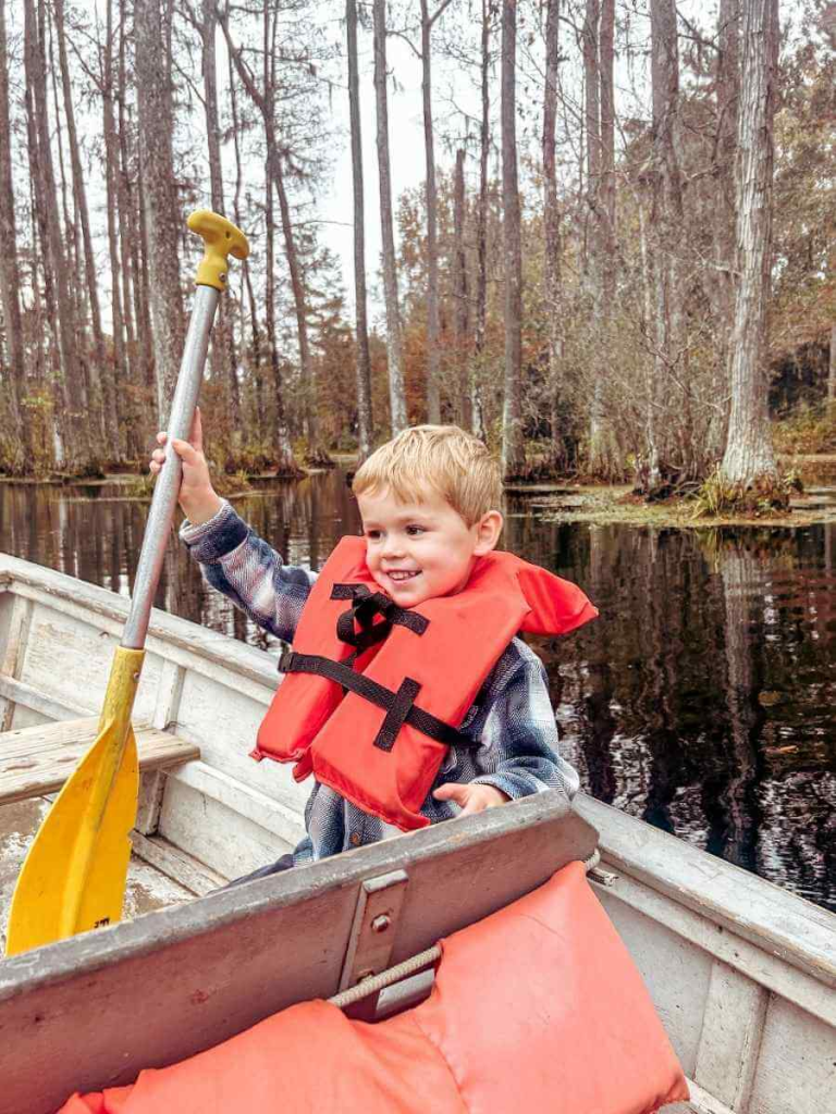 Child enjoying a boat ride through Cypress Gardens, a secret place to take photos in Charleston.