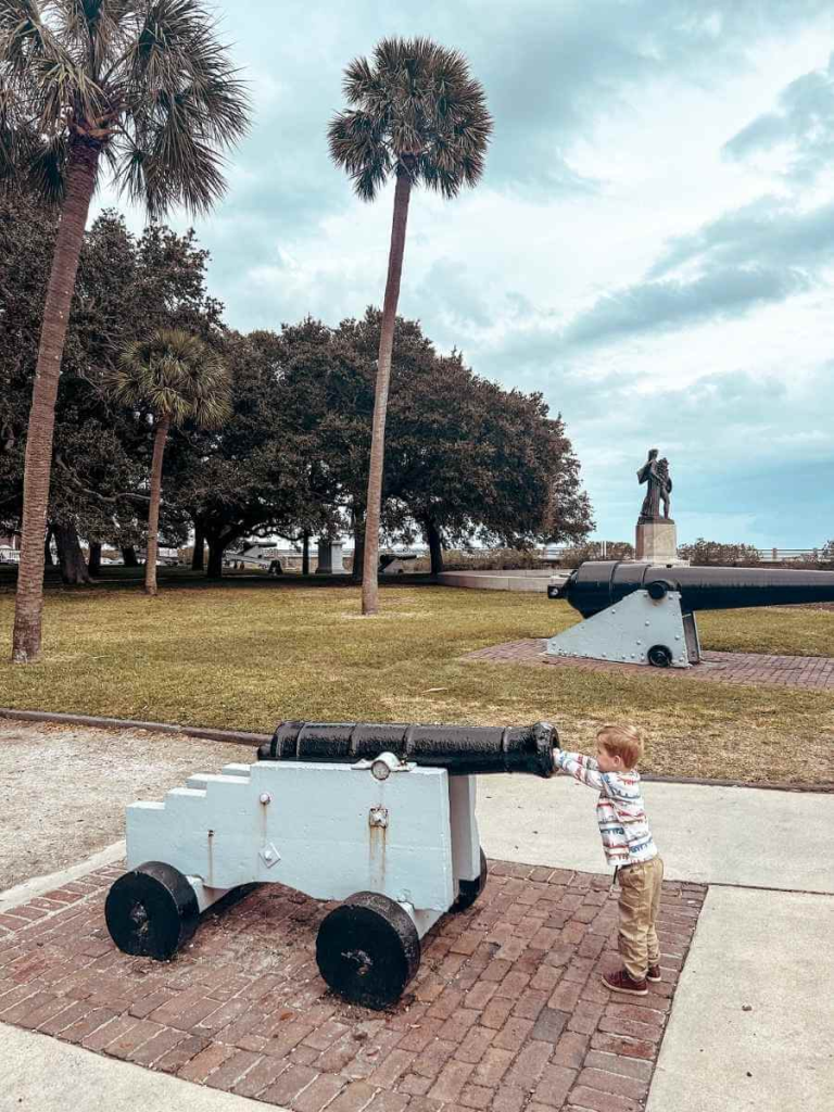 A young child pretending to load a ball in to a cannon, a fun thing to do in Charleston with kids.