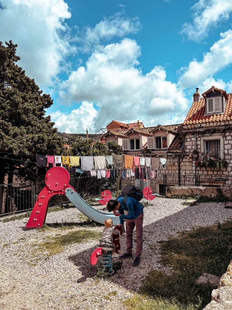 Children playing in an Old Town Dubrovnik playground with traditional laundry lines in the background.