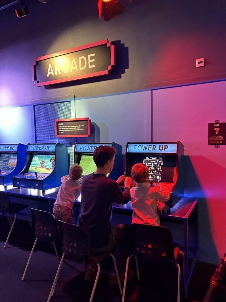 Family playing video games in the Power Up exhibition, an ideal activity for older children.