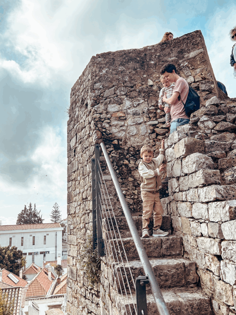 Family exploring and climbing the ancient stone walls of Tavira Castle