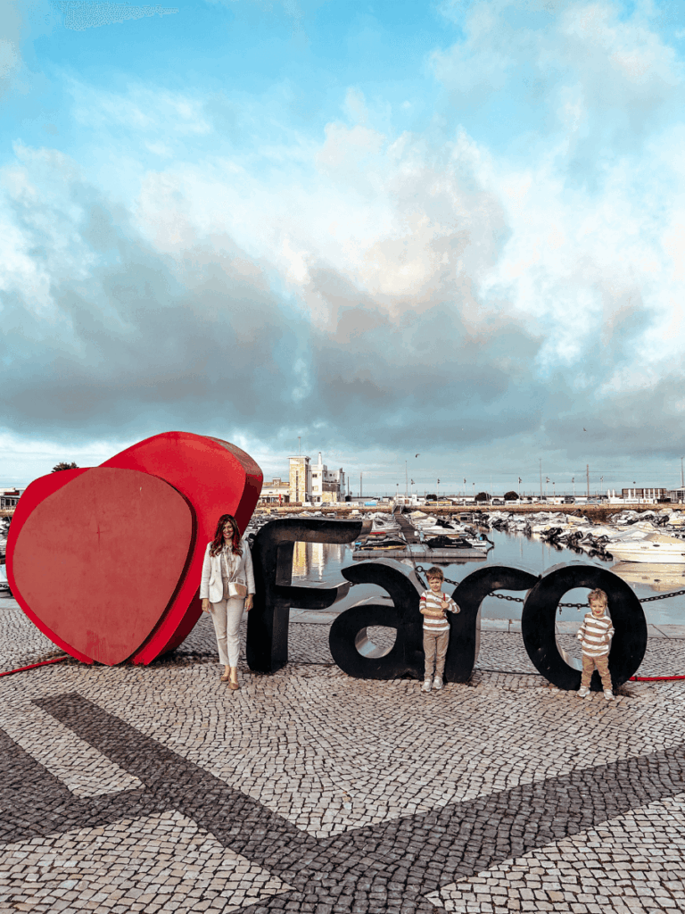 Posing with the Faro Sign as a family on our one week Algarve, Portugal itinerary