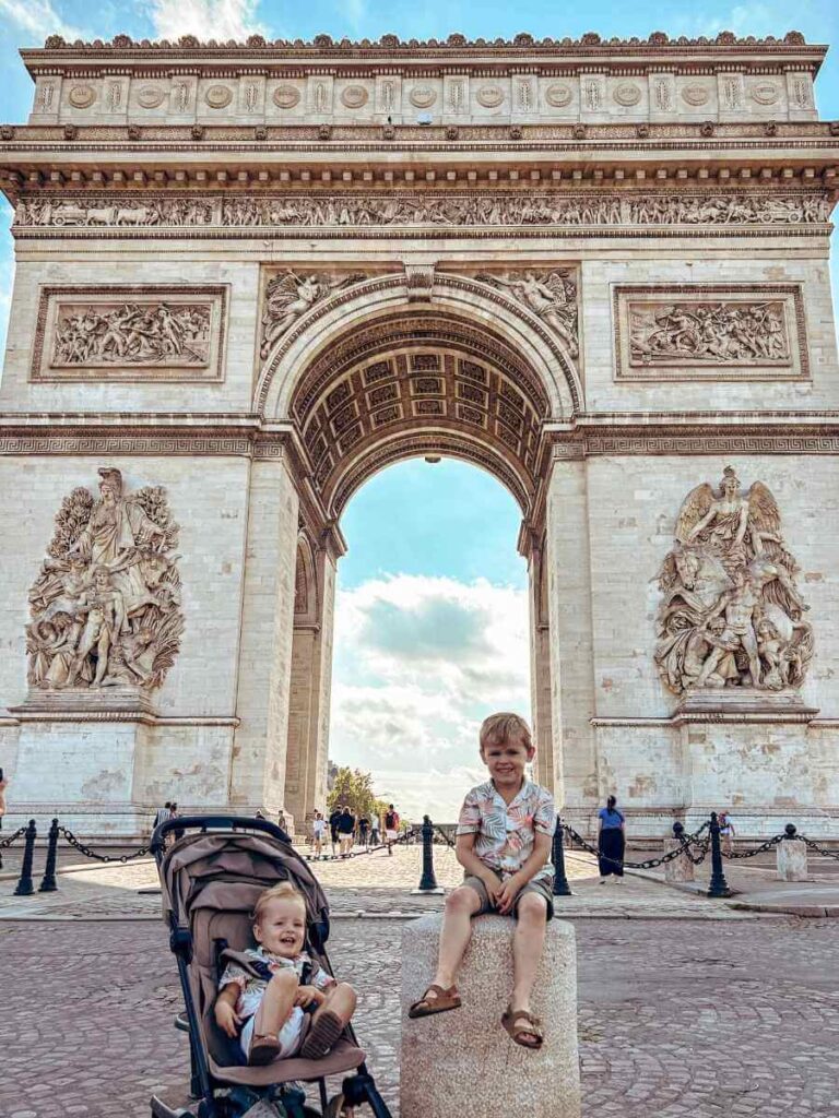 Two young children in front of the Arc de Triomphe during a family-friendly trip to Paris with a toddler