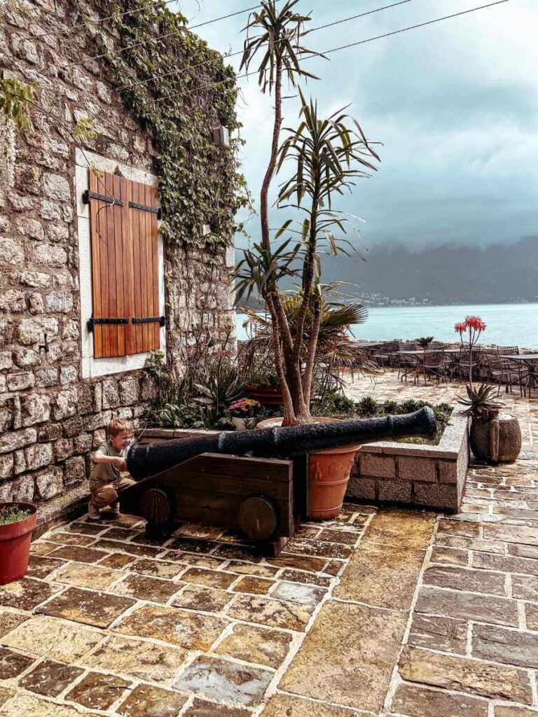 Young boy playfully pretending to fire a historic cannon at the Citadel in Budva