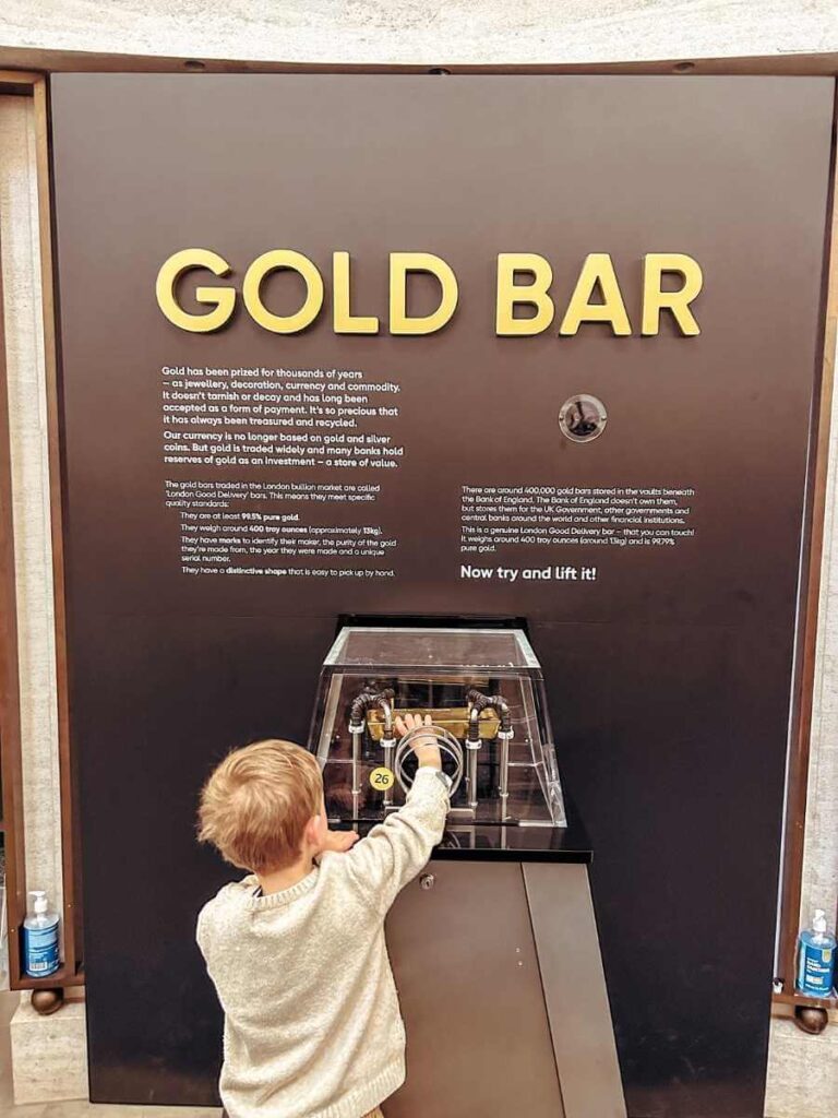 Young child trying to lift a real gold bar at the Bank of England Museum
