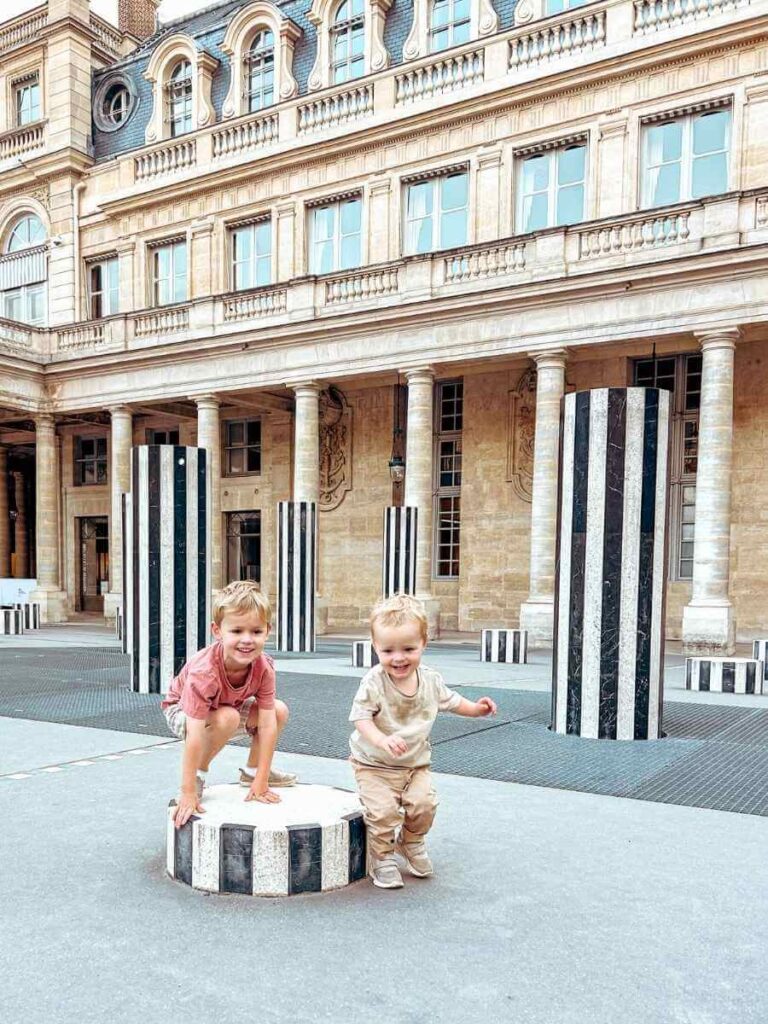 Two young children jumping and playing on the striped columns at Palais Royal, a perfect ting to do in Paris with a toddler