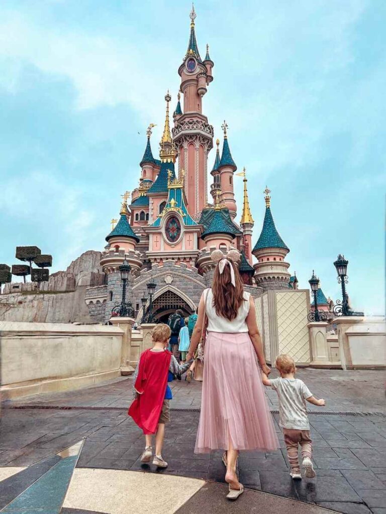 Family walking under Sleeping Beauty’s Castle at Disneyland Paris, the perfect day trip form Paris with a toddler or children.