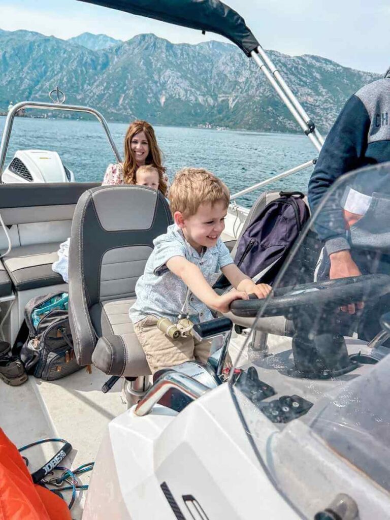My son steering a speedboat during a guided family boat tour in Kotor