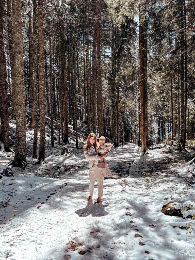 Mother carrying baby in a carrier while walking near Black Lake in Durmitor National Park, Montenegro