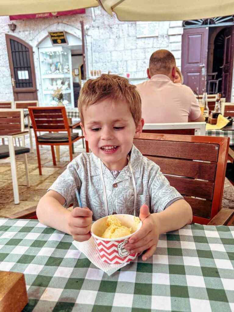Child enjoying an ice cream treat on a sunny day in Kotor, Montenegro.