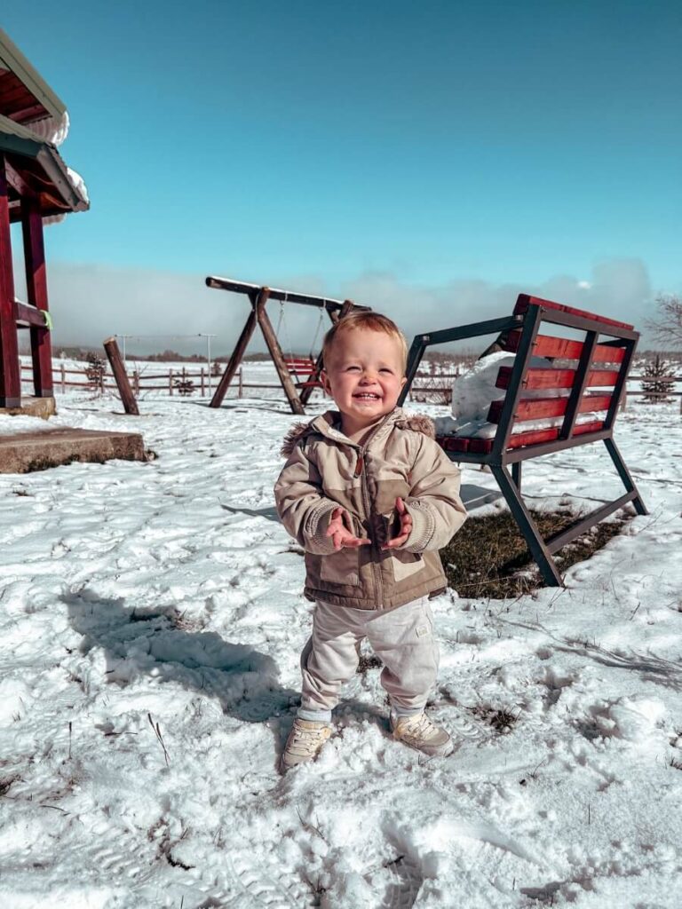 Toddler bundled up and smiling while playing in the snow in Zabljak