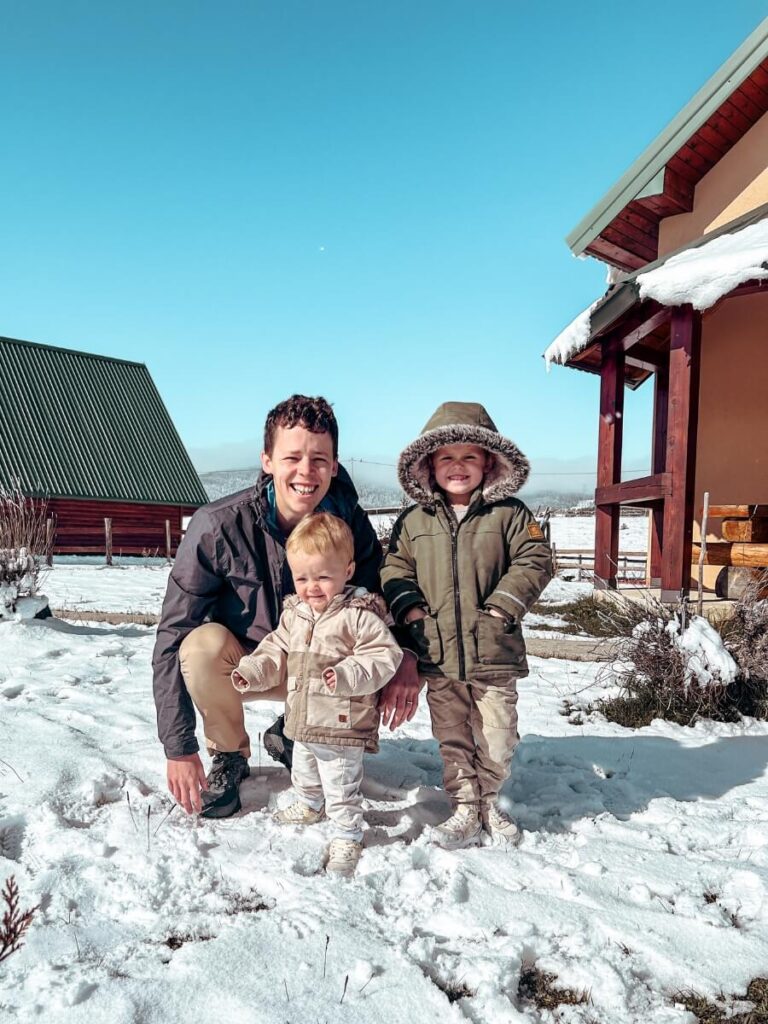 Father and two young children playing in the snow together in Zabljak