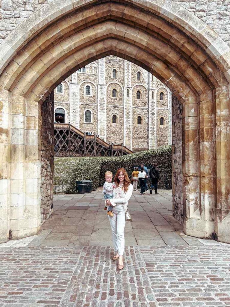 Mum in the City holding baby outside the entrance to the Tower of London on a family day out