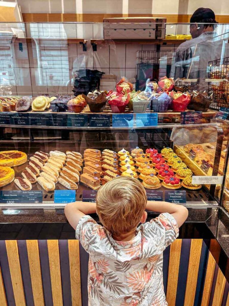 Child looking at colourful pastries in a Paris patisserie