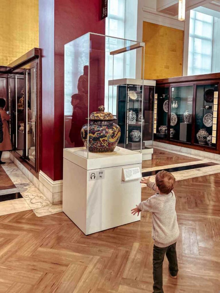 Child closely observing an ancient artifact at the British Museum London with kids