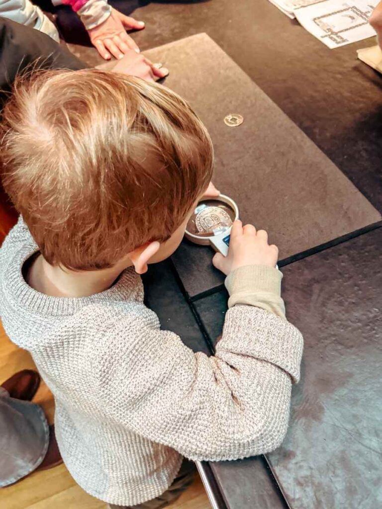 Child using a magnifying glass at the hands-on learning desk in the British Museum