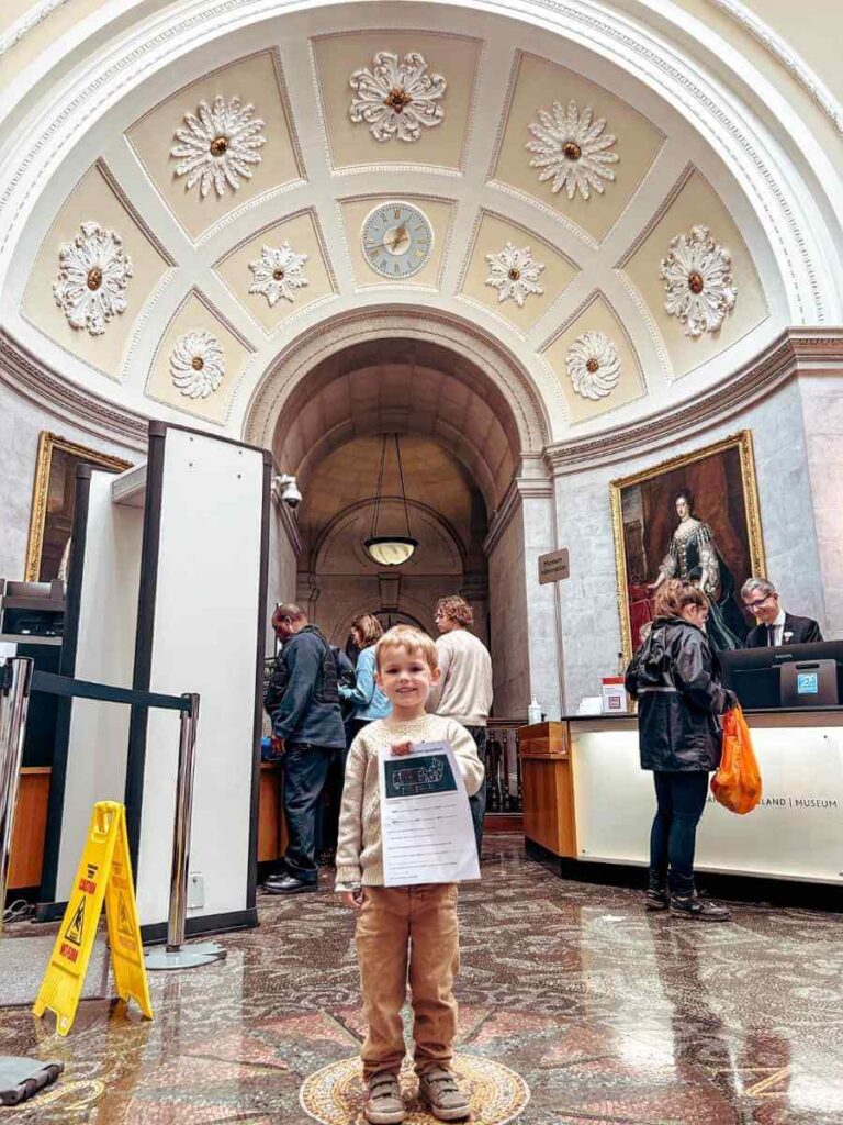 Child holding a completed kids’ activity worksheet from the Bank of England Museum