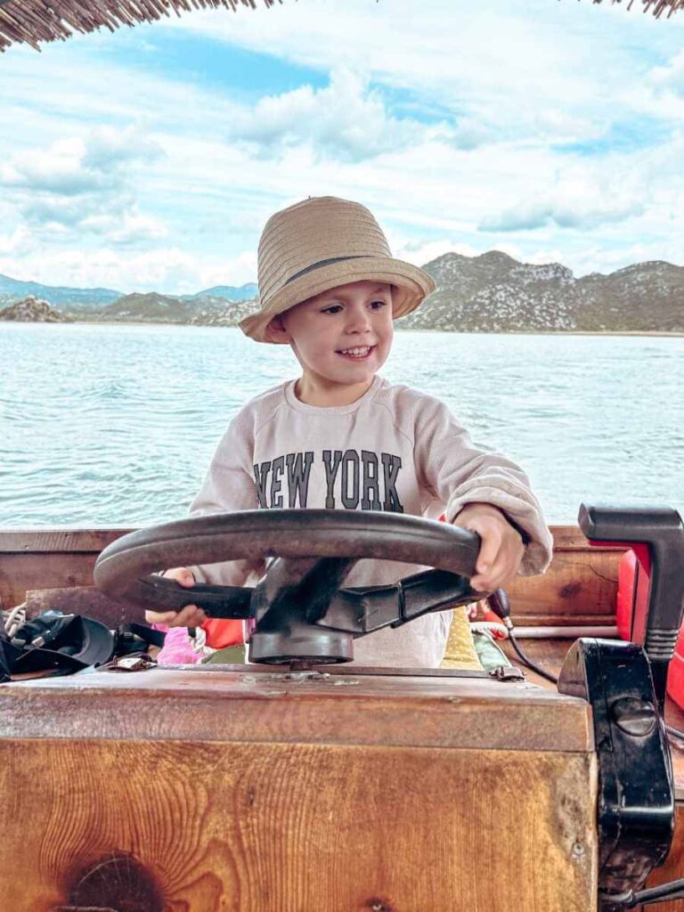lose-up of child steering the boat on a Lake Skadar family boat tour in Montenegro