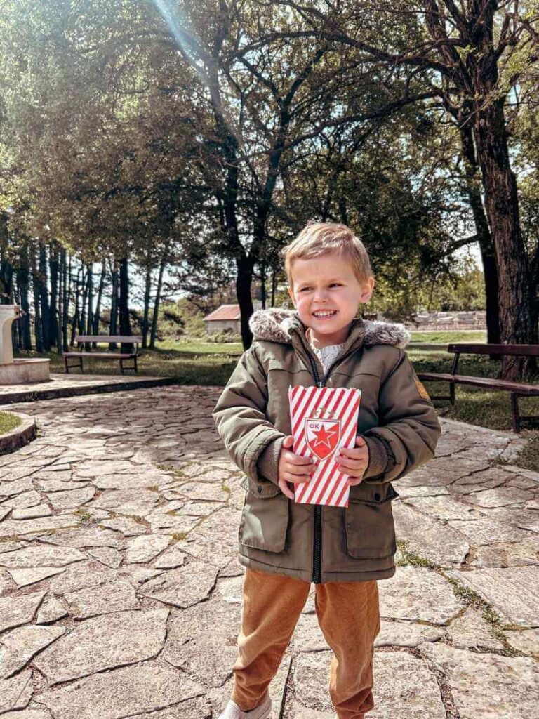 Young child holding a bag of popcorn in City Park, Niksic Montenegro