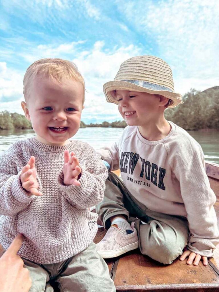 Two smiling children on a family boat tour of Lake Skadar, Montenegro