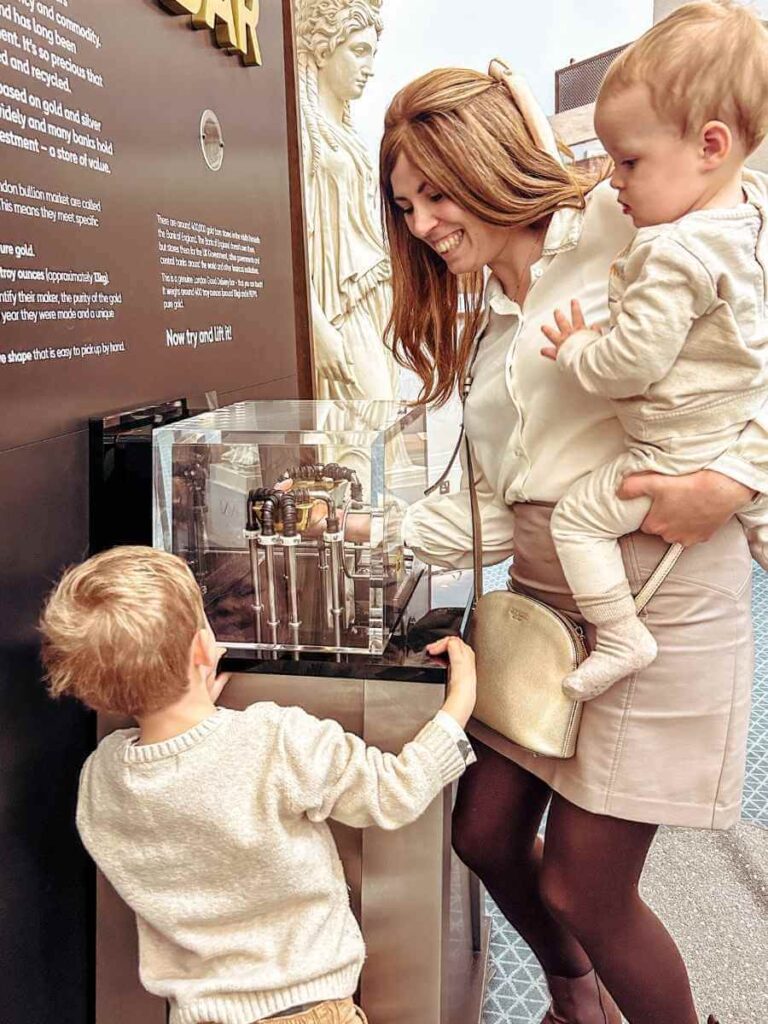 Mum in the City attempting to lift a gold bar at the Bank of England Museum exhibit