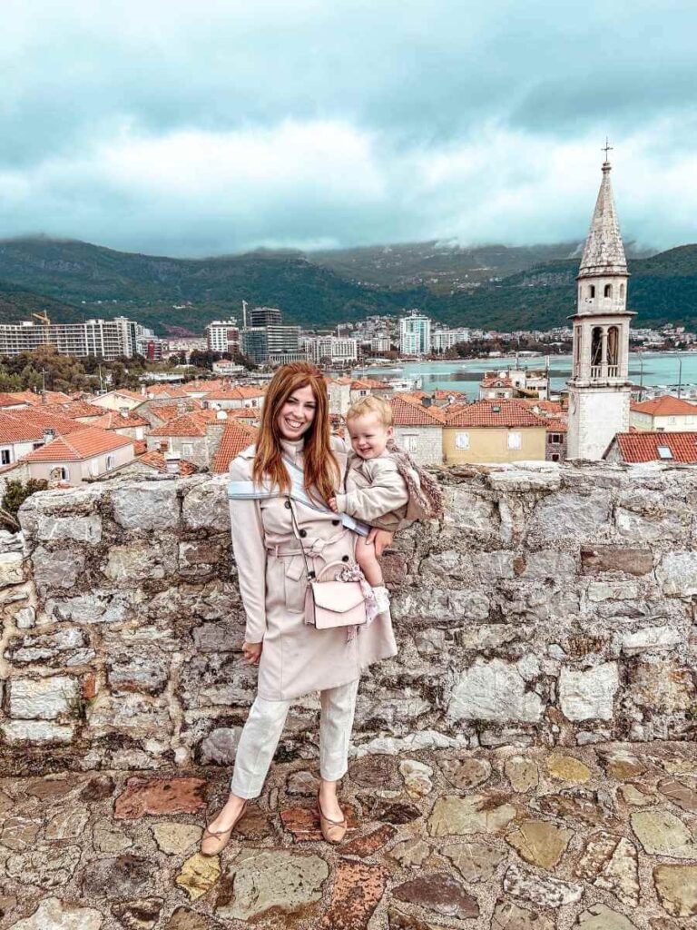 Mum holding her baby with panoramic views of Budva's Old Town from the top of the Citadel