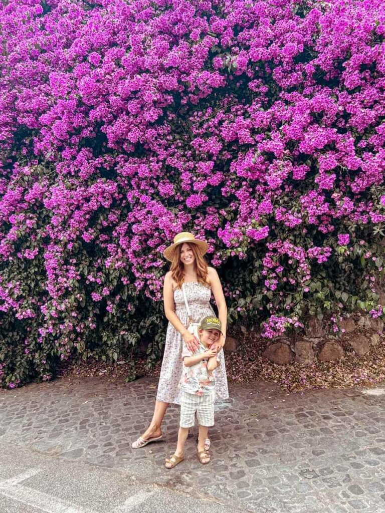 mother and son standing near vibrant pink blossoms in Villa Borghese, capturing the beauty of spring in one of Rome’s prettiest parks.