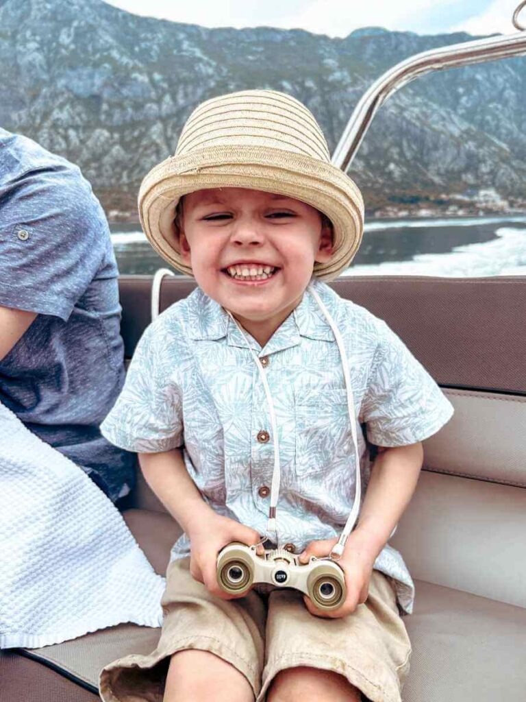 Happy child enjoying a boat ride along the Bay of Kotor coast during a family tour