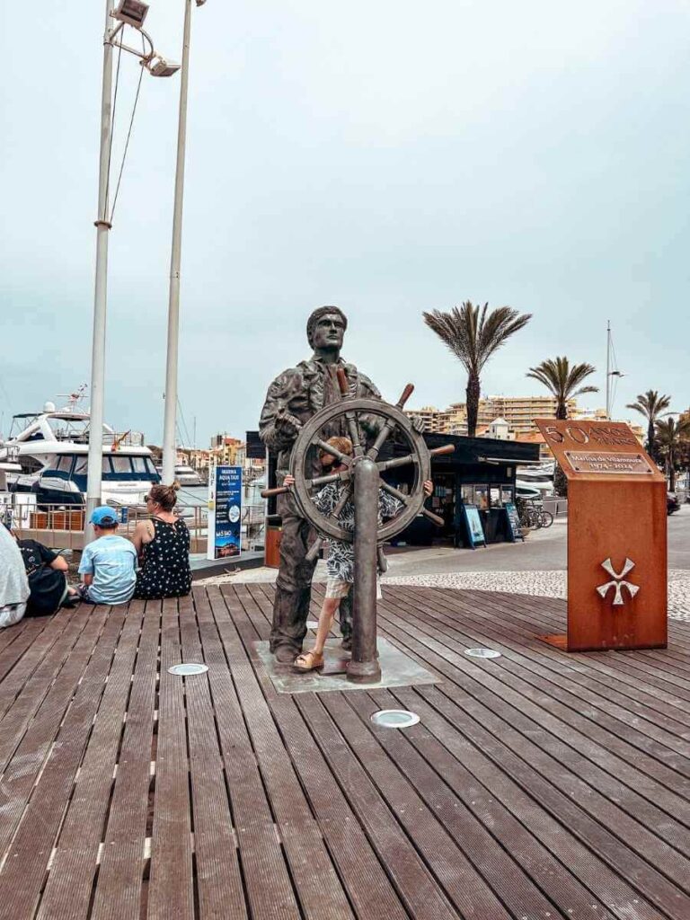 Bronze sailor sculpture overlooking Vilamoura Marina, a popular photo spot for families