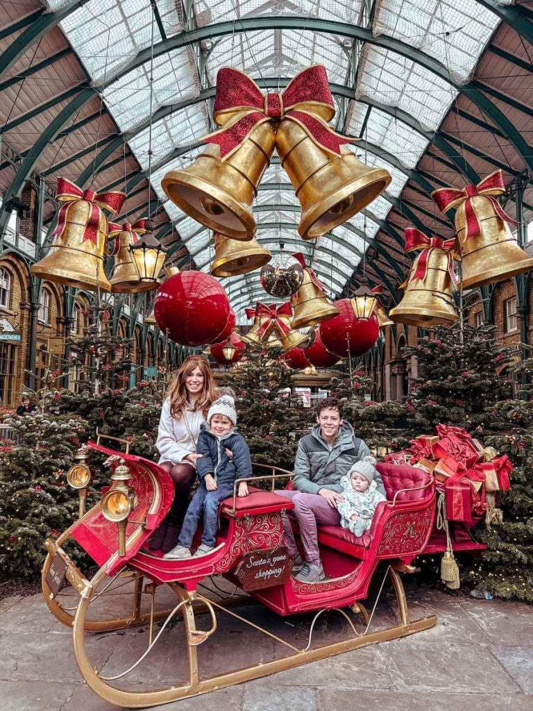 Family in a giant sleigh display in Covent Garden, London at Christmas