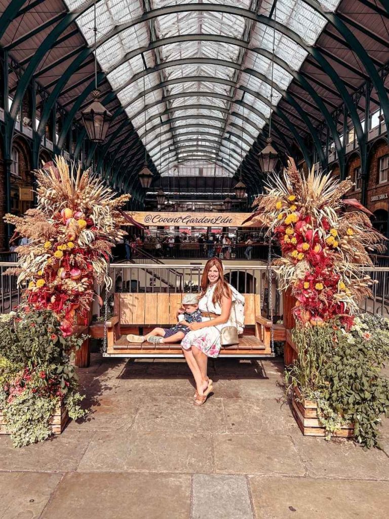Mum in the City and her son posing with a floral display in Covent Garden on a first trip to London