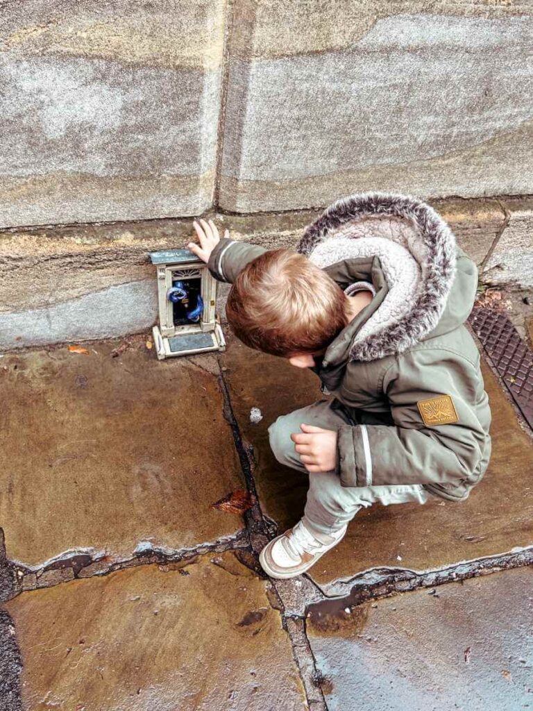 Child spotting a tiny Dinky Door – part of a quirky and fun trail in Cambridge for kids.