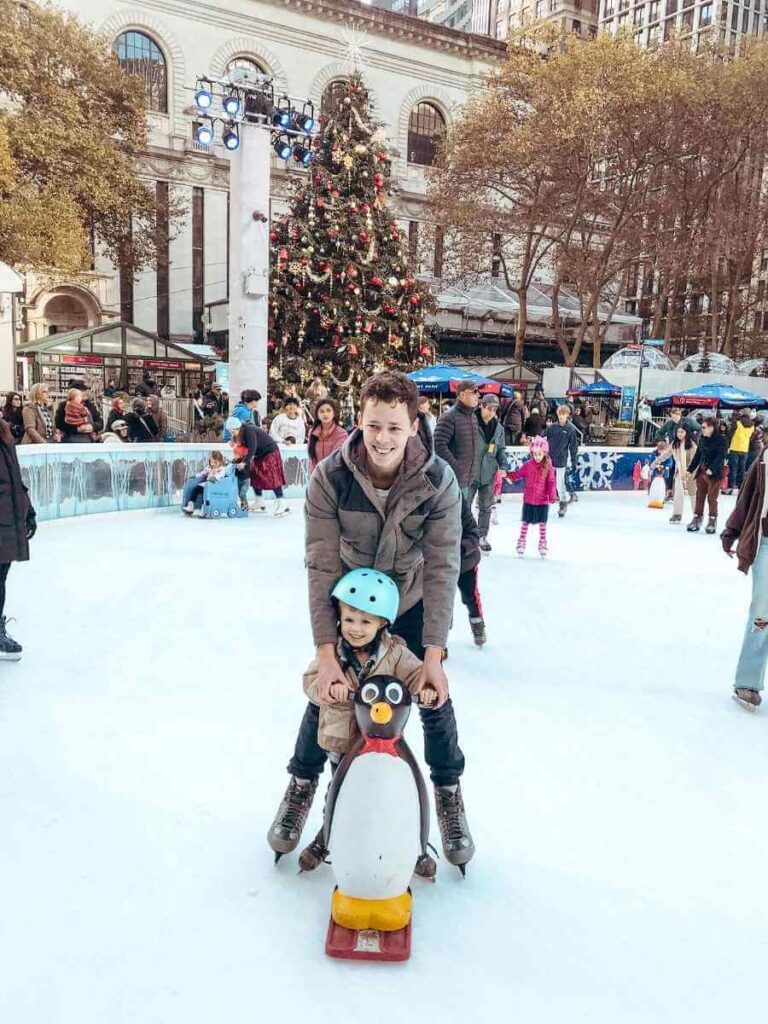 Bryant Park ice skating rink with child-friendly penguin skate aids — a top thing to do when spending Christmas in New York as a family.