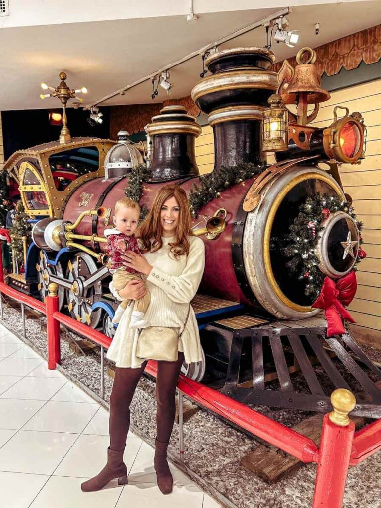 Outside Macy’s Santaland in NYC with festive Christmas train display, a top holiday activity with kids.