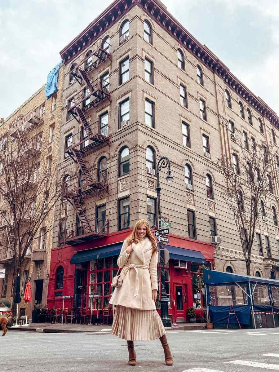 Feminine, neutral winter outfit, a classic wool coat styles over a pleated midi skirt and long boots.