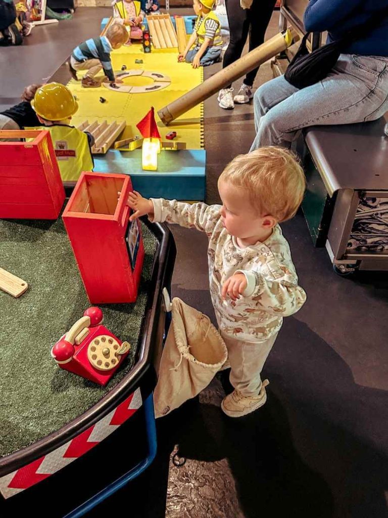 Toddler sorting shapes into a post box at the Post & Play activity space in The Postal Museum.
