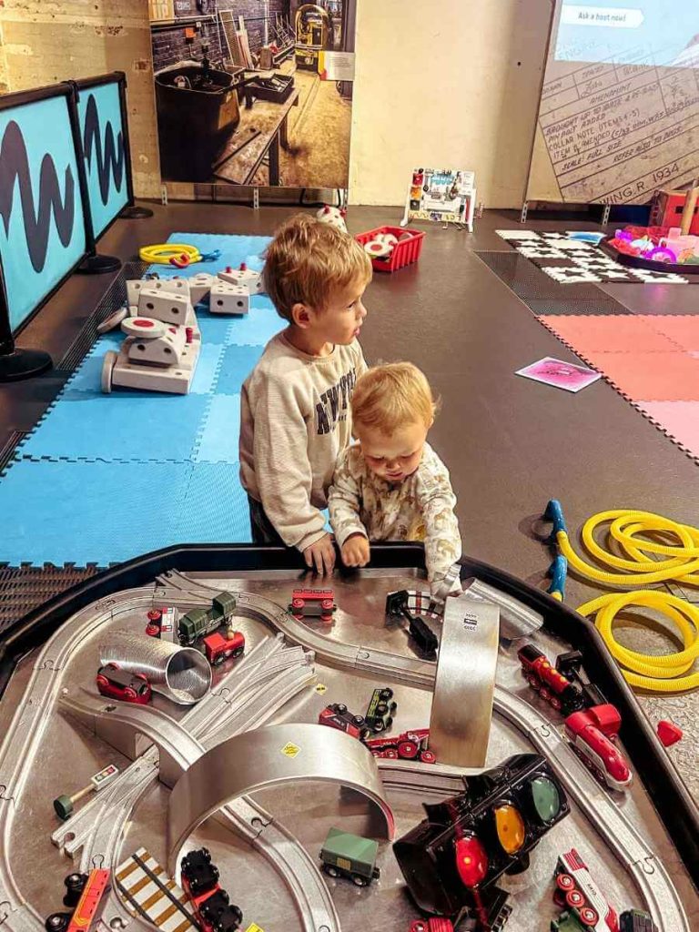 Children building and playing with a car track in the Post & Play toddler area at The Postal Museum.