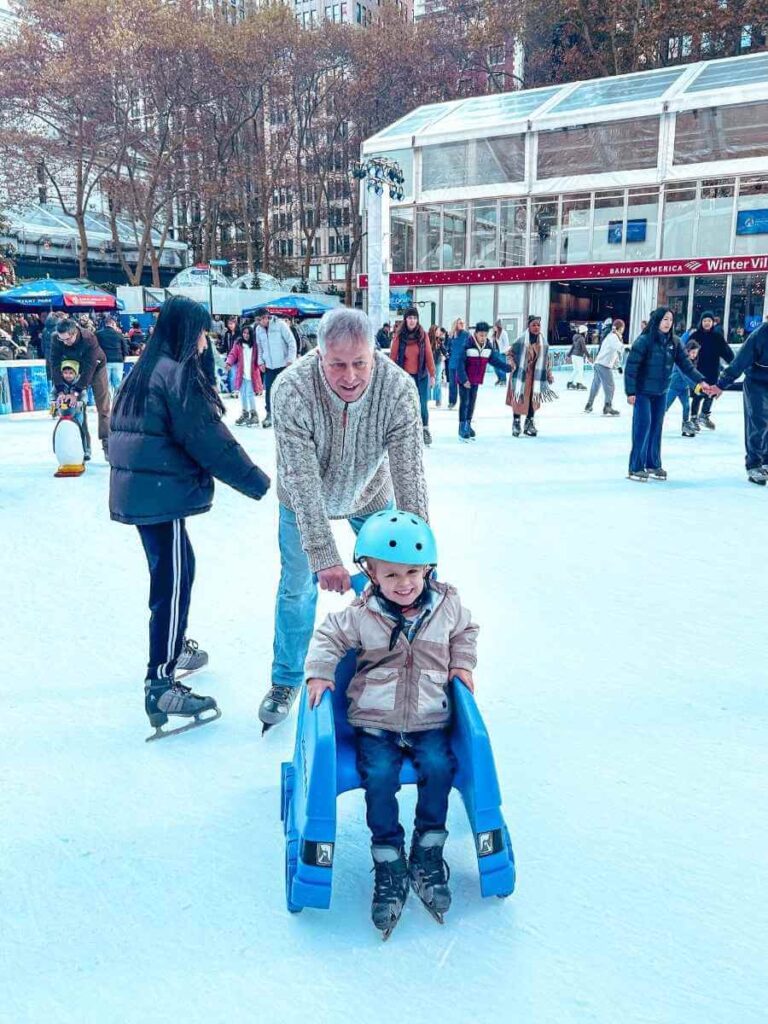 Bryant Park ice skating rink with toddler-friendly skate aids — a top thing to do in NYC at Christmas with toddlers.
