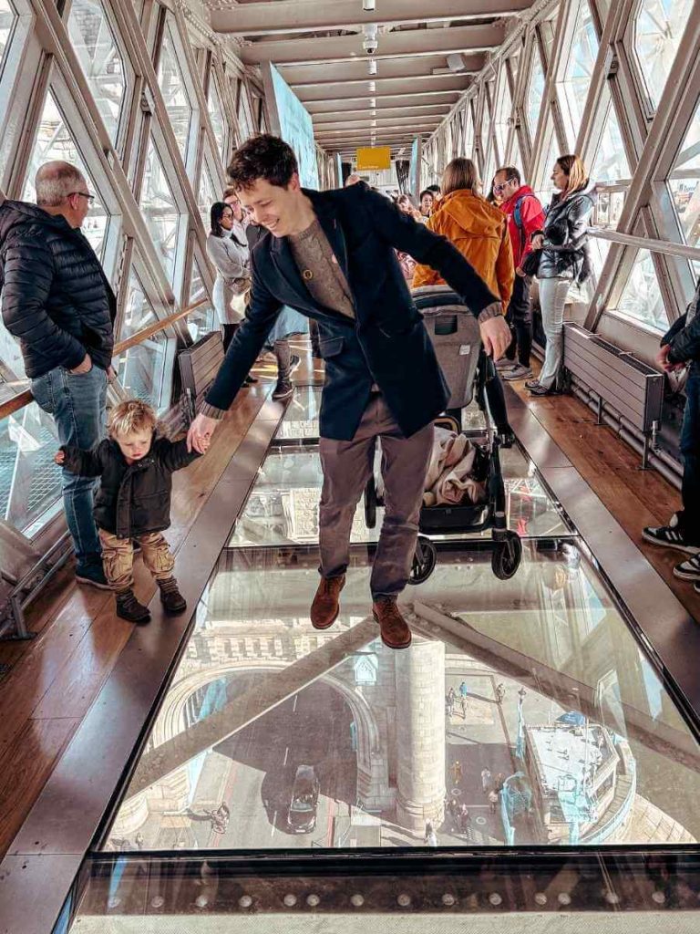 Toddler carefully walking along the safe edge of Tower Bridge glass walkway in London