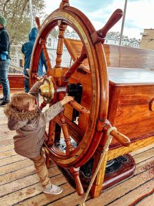 Child steering the ship’s wheel on the Cutty Sark’s top deck, a popular interactive feature.