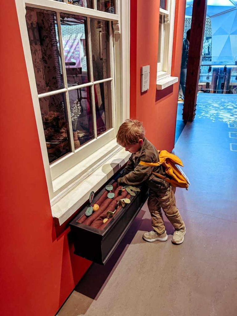 Child playing with an interactive vegetable planting game at the Museum of the Home