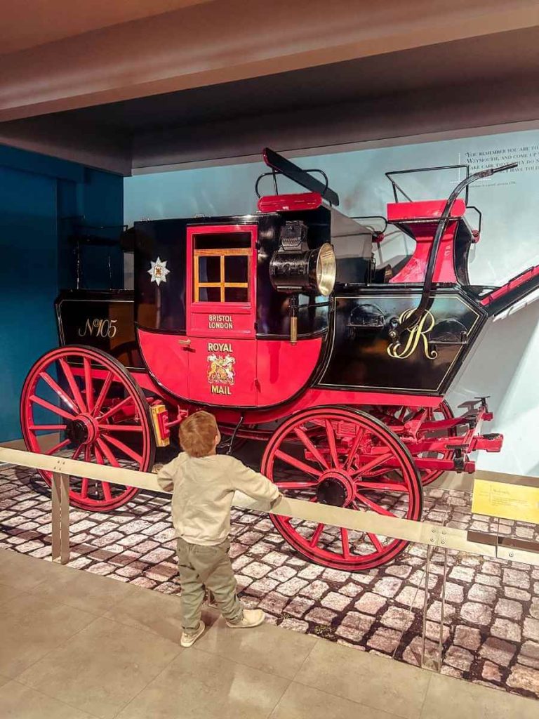 Child looking an old mail carriage on display at The Postal Museum, London.