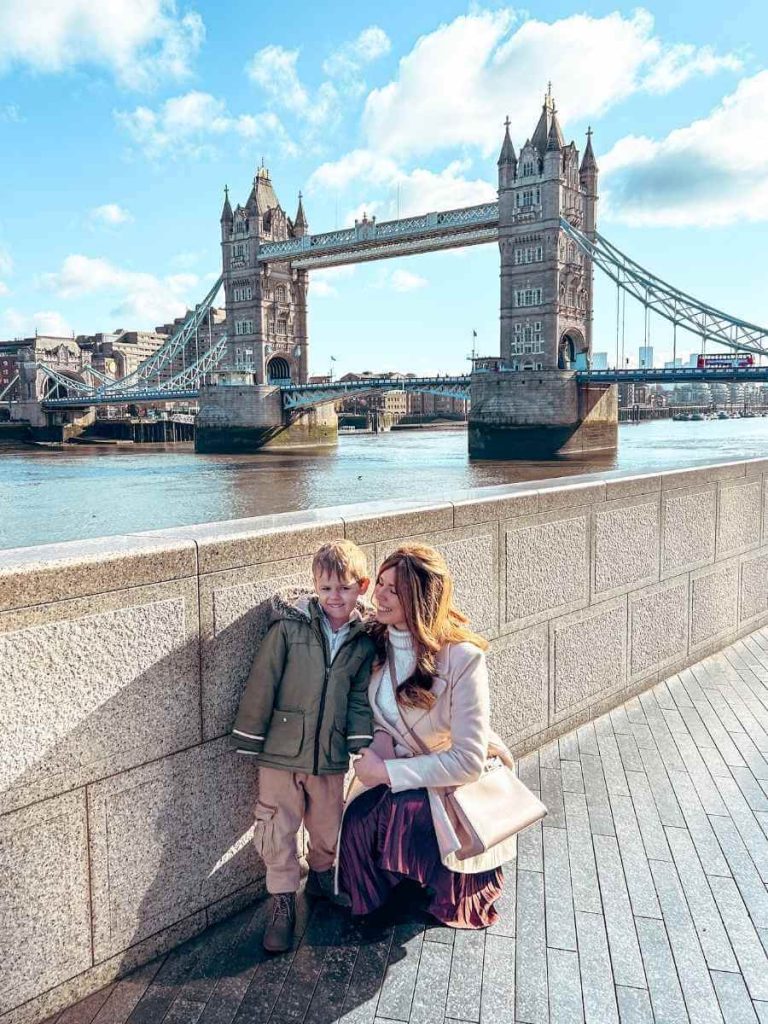 Mum in the City and her son posing in front of Tower Bridge London on a family trip with kids