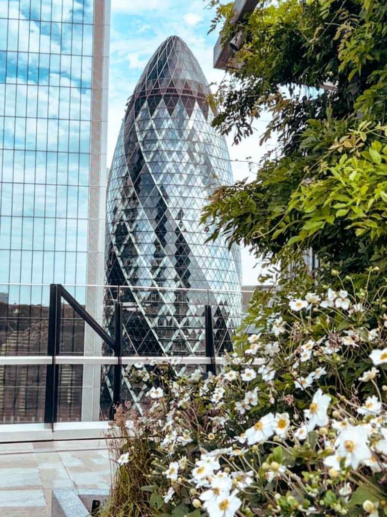 The Gherkin seen from The Garden at 120 rooftop with flowers in the foreground