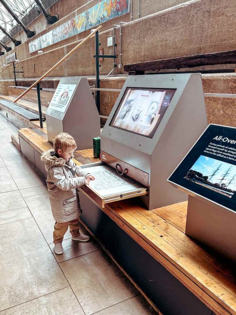 Child engaging with an interactive activity in the dry dock area beneath the Cutty Sark.
