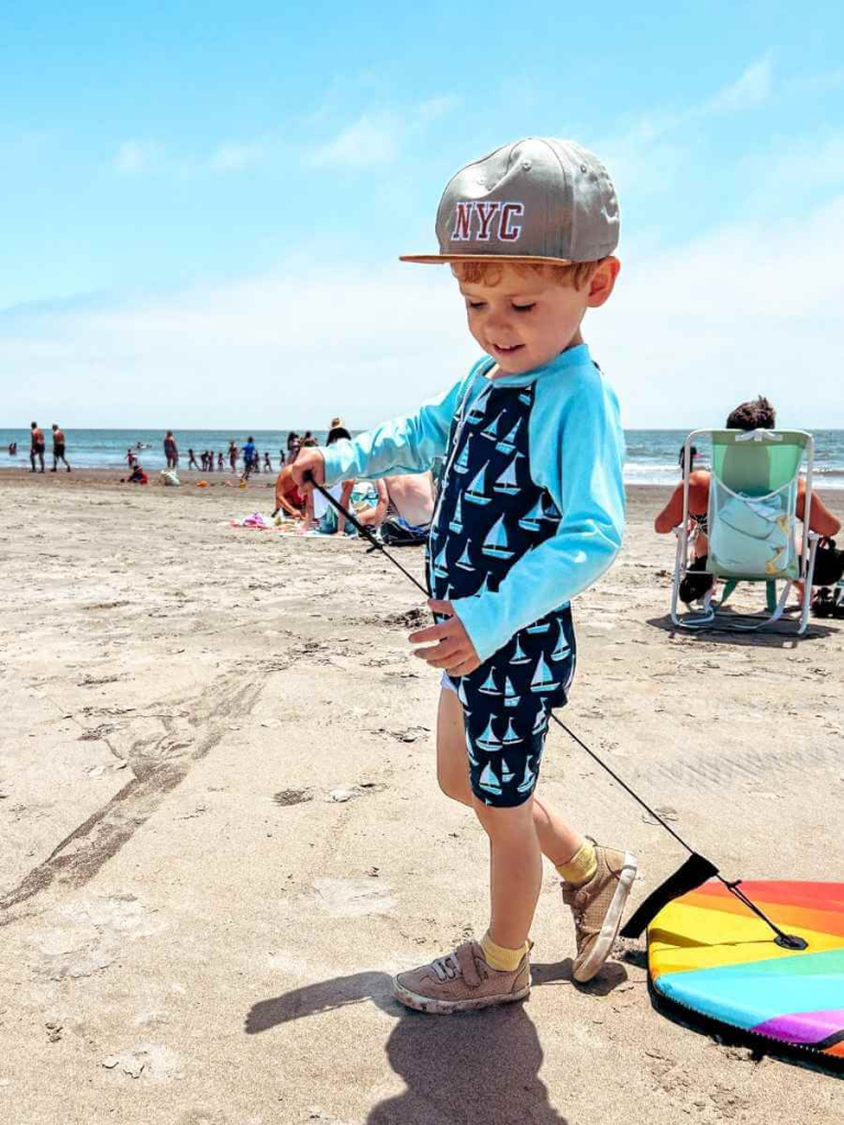 Toddler pulling a body board on Coronado Beach during a sunny family day out in San Diego