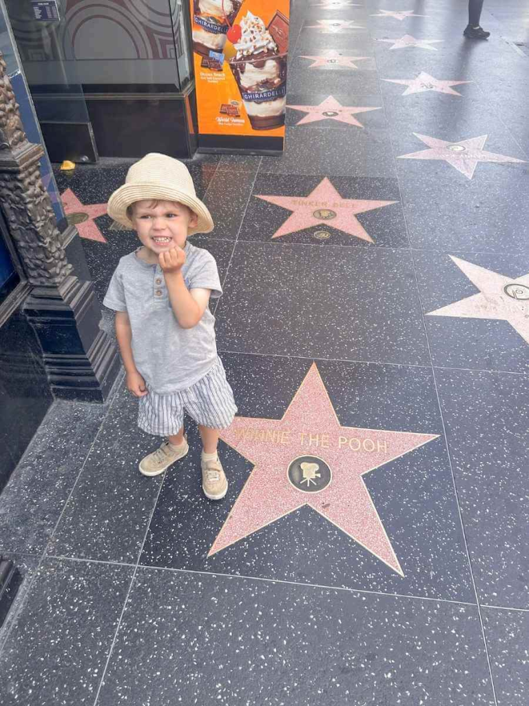 My toddler smiling by the Winnie the Pooh star on the Hollywood Walk of Fame – a highlight for kids on a Los Angeles family vacation.